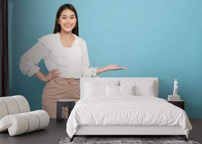 Young beautiful asian woman with smart casual cloth smiling and presenting copy space isolated on blue background Wall mural