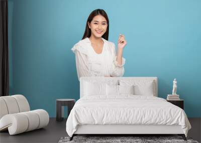 Young beautiful asian woman with smart casual cloth smiling isolated on blue background Wall mural