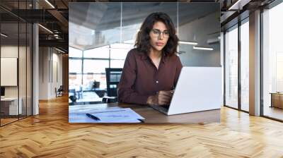 Busy 30s latin hispanic middle age business woman working on laptop computer in office. Focused Indian young businesswoman professional entrepreneur using pc, thinking analysing project at workplace Wall mural