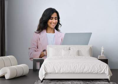 Focused young middle eastern Israel businesswoman using laptop pc online application for work isolated on white wall. Indian or arabic woman in business suit holding computer, doing data base research Wall mural