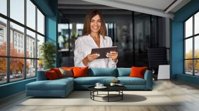 Latin Hispanic 40s years mature business woman looking at camera. smiling European businesswoman CEO holding digital tablet using fintech tab online application standing in modern office, copy space Wall mural