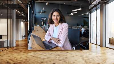 Portrait 30s latin hispanic business woman manager working on laptop computer in modern office. Smiling Indian young businesswoman professional entrepreneur using pc app at workplace looking at camera Wall mural