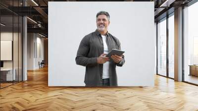 Portrait of 40s Hispanic bearded mature adult professional business man. Happy smiling Indian senior businessman CEO holding digital tablet using tab application standing on isolated white background Wall mural