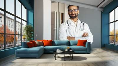 Portrait of male doctor wearing white lab coat, stethoscope standing and looking at camera in clinic hall. Arabian indian therapist, general practitioner headshot. Medicine, heal insurance, healthcare Wall mural