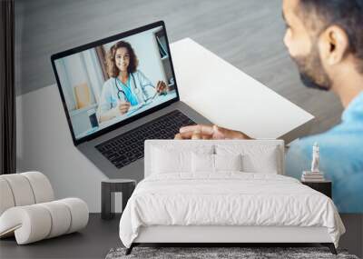 View over male client shoulder sit at desk receive medical consultation online from female doctor. Indian man listening practitioner. Distant communication, health protection and telemedicine concept Wall mural