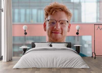 Young ginger irish man in glasses smiling with pleased happy expression and looking at camera portrait. Millennial male freelancer successful entrepreneur,young businessman standing in office. Slow mo Wall mural