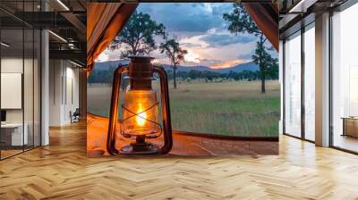 A warm lantern glows inside a canvas tent at dusk Wall mural