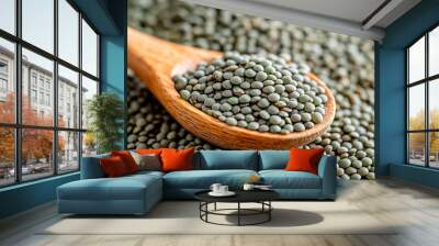 Green lentils in a wooden spoon on a backdrop full of green lentils Wall mural