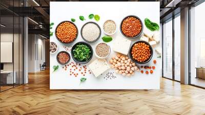 Variety of legumes, spices, and fresh greens arranged aesthetically on a white surface with a centerpiece of sliced tofu Wall mural