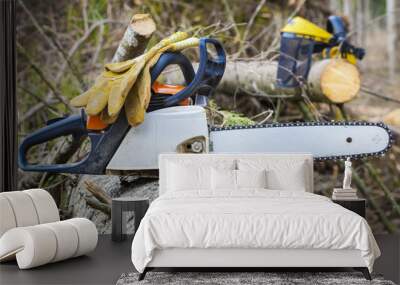 Chainsaw and gloves on tree Wall mural