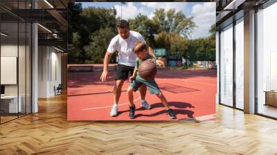 Father and son at public basketball court playing basketball. Wall mural