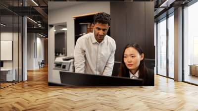 Shot of two businesspeople discussing something on a desktop computer. Wall mural