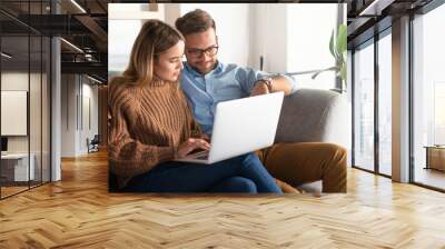 Young couple ordering online, looking in laptop	 Wall mural