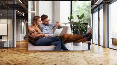 Young couple ordering online, looking in laptop Wall mural