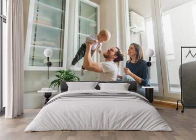 Young parents playing with baby Wall mural