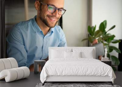 Young smiling Man typing on digital tablet	 Wall mural