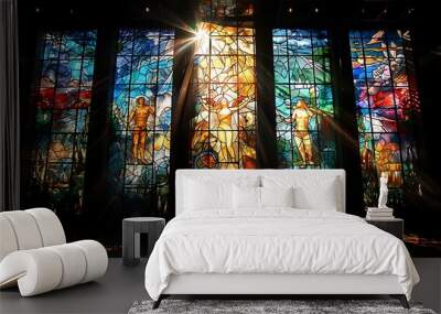 Adam Eve depicted in a series of stained glass windows where light filters through vibrant colors to illuminate their timeless journey through religious symbolism Wall mural