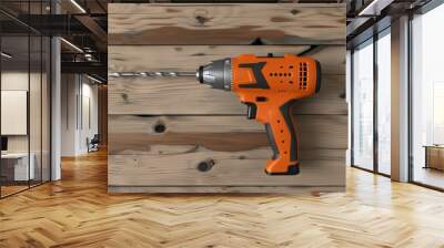 Orange electric drill on a wooden surface. Power tool for construction and DIY projects. Wall mural