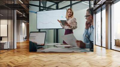 Business woman making presentation at modern tv office. Coach pointing at screen Wall mural