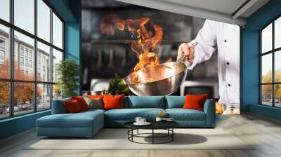 Chef hands keep wok with fire. Closeup chef hands cook food with fire. Wall mural