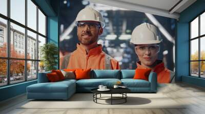 Couple successful factory engineer posing in modern facility in helmets closeup. Wall mural