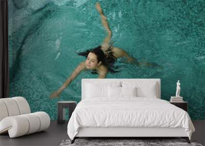 Slim body girl relaxing in pool. Gorgeous woman swimming in luxury spa center. Wall mural