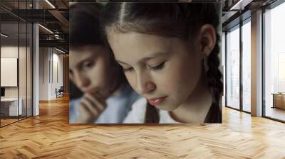 Two schoolgirls sitting together at break close up. Preteen girls looking down. Wall mural