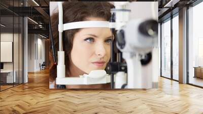 Pretty woman is looking into eye test machine with concentration in oculist lab Wall mural