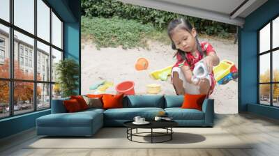 Asian baby girl playing sand outdoor. Kid building sand castle. Wall mural