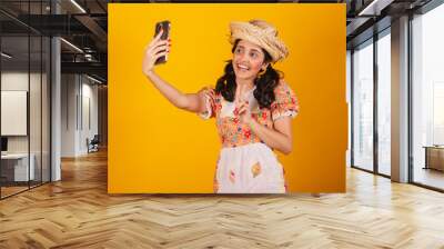 Beautiful brazilian woman, with festa junina clothes, taking self portrait with smartphone. Wall mural