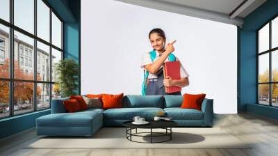 Asian Indian teenage schoolgirl in school uniform with different expressions standing against white Wall mural