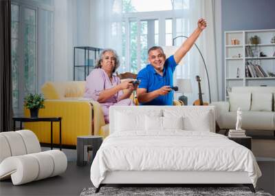 Happy Indian asian mid age couple having fun, playing video game together Wall mural