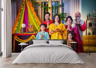 Indian Asian family performing Ganesh Puja at home in traditional attire, celebrating with devotion Wall mural