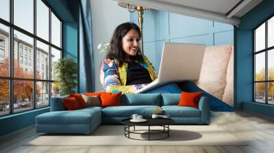 Indian asian pretty woman using laptop computer or tablet, sitting on sofa Wall mural