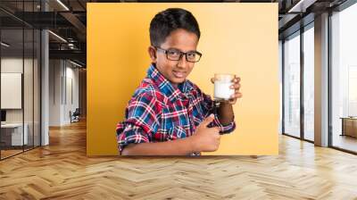 indian boy with a glass of milk, indian kid drinking milk, indian boy drinking milk,asian boy and milk, closeup portrait on yellow background Wall mural