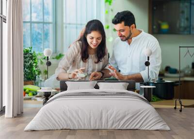 Indian couple in kitchen - Young Beautiful asian wife enjoying cooking with husband. Wall mural