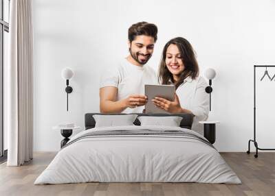 Indian couple using tablet computer while standing isolated over white background Wall mural