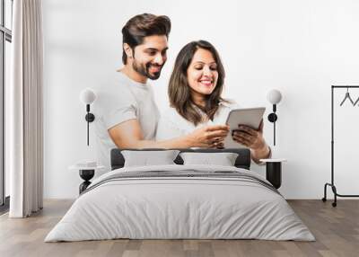 Indian couple using tablet computer while standing isolated over white background Wall mural