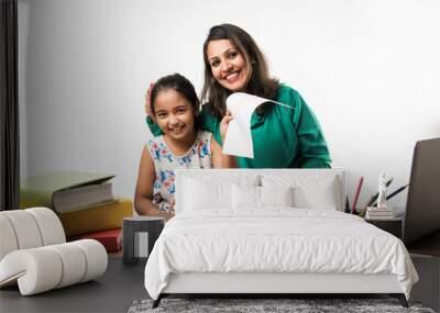 Indian girl studying with mother or teacher at study table with laptop computer, books and having fun learning Wall mural