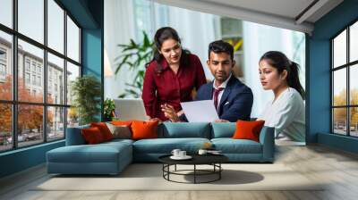 Indian young businesspeople using laptop in group meeting at desk Wall mural