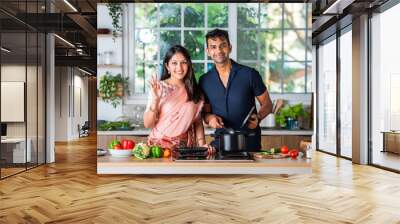 Indian young husband wife preparing food in the kitchen Wall mural