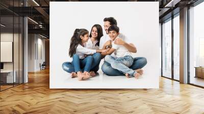 playful indian/asian family sitting isolated over white background. selective focus Wall mural