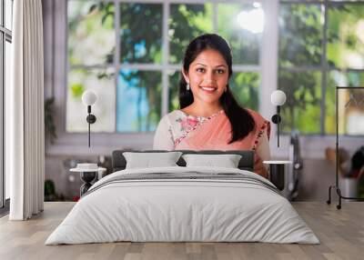 Portrait of happy Indian asian young woman wears saree while working in kitchen Wall mural