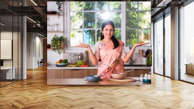 Portrait of happy Indian asian young woman wears saree while working in kitchen Wall mural