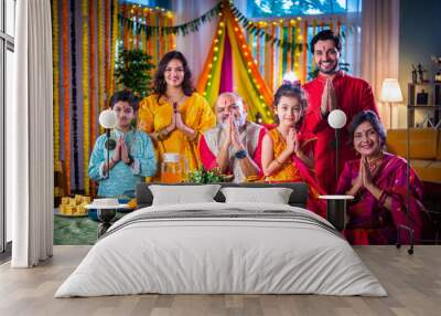 Portrait of happy Indian family in traditional outfit celebrating Diwali together at home eating food. Wall mural