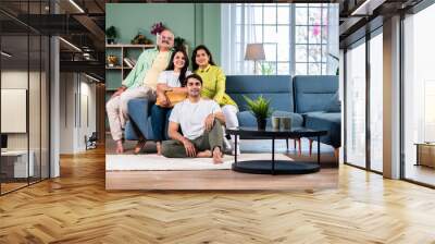 Portrait of happy Indian family of four sitting in modern living room Wall mural