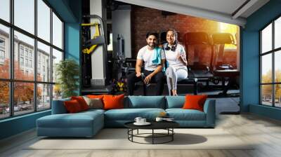 Portrait of Indian asian young Couple working Out Together in Gym, Training With fitness Equipments Wall mural