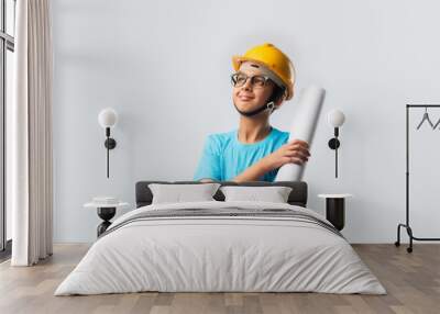 Portrait of Indian kid posing as an engineer or architect, wears yellow safety helmate and blueprint Wall mural