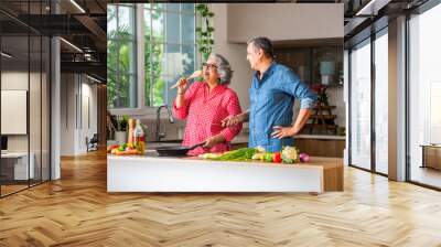 Senior Indian asian couple in kitchen, cooking healthy food together and happy in retirement lifestyle. Wall mural