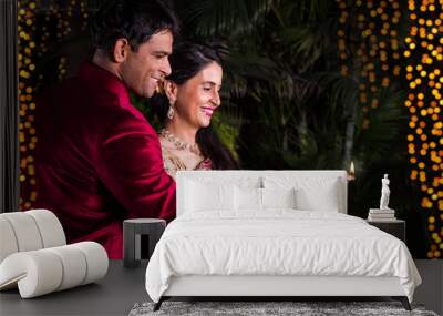 smart looking indian young husband and wife in traditional wear holding a plate full of motichoor la Wall mural